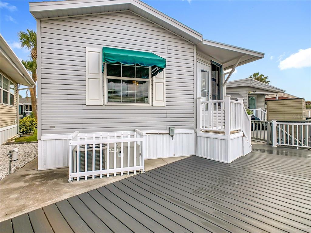 A gray mobile home exterior features a wooden deck, a white railing, and an awning — 9000 US HWY 192 UNIT 324, CLERMONT, FL