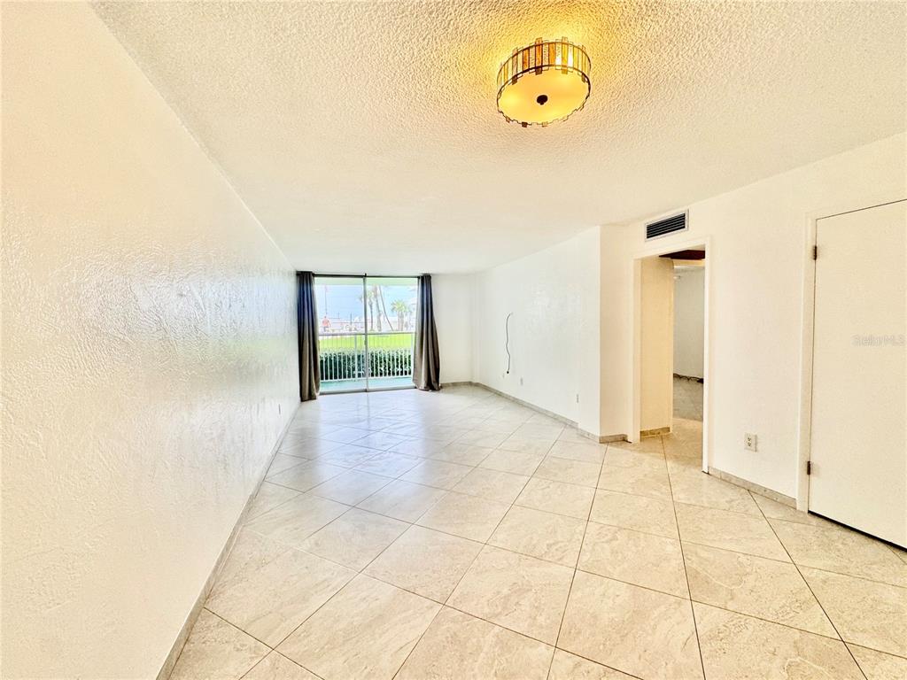 An empty room with light-colored tile flooring, white walls, and a sliding glass balcony door — 2727 N ATLANTIC AVENUE UNIT 1100, DAYTONA BEACH, FL