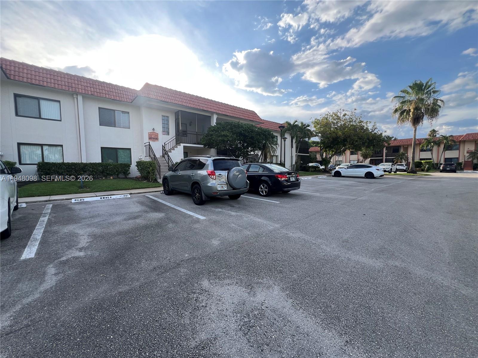 A two-story apartment building with a red tile roof overlooks a paved parking lot — 379 Lakeview Dr # 205, Weston FL 33326, WESTON, FL