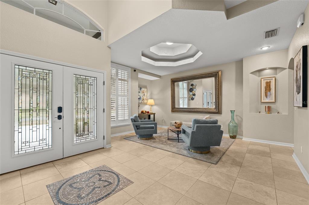 A bright foyer features tile flooring, a decorative inlay, two armchairs, and a large mirror — 9502 PORTBURY DRIVE, ORLANDO, FL
