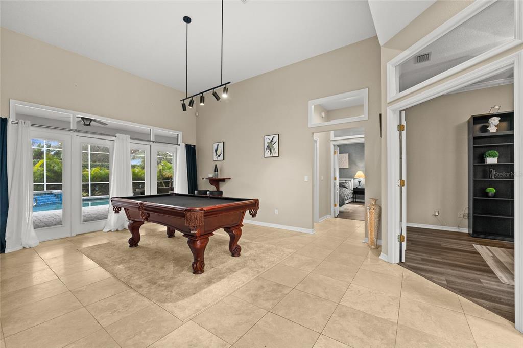 A game room features a pool table, tile flooring, and glass doors leading to a pool — 9502 PORTBURY DRIVE, ORLANDO, FL