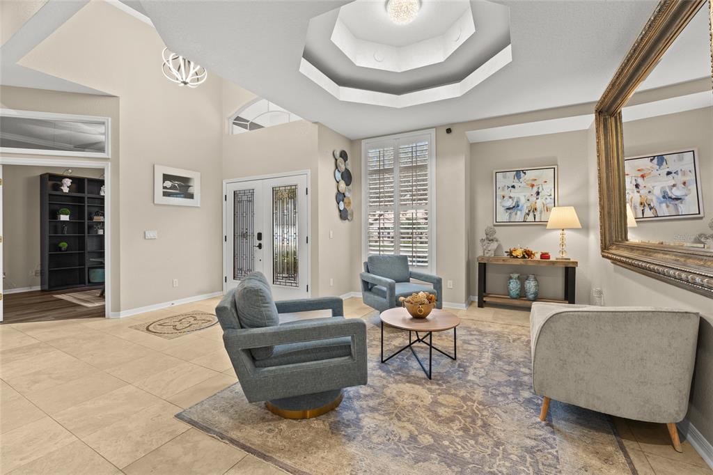 A bright foyer features a high tray ceiling, tiled floors, and a seating area — 9502 PORTBURY DRIVE, ORLANDO, FL