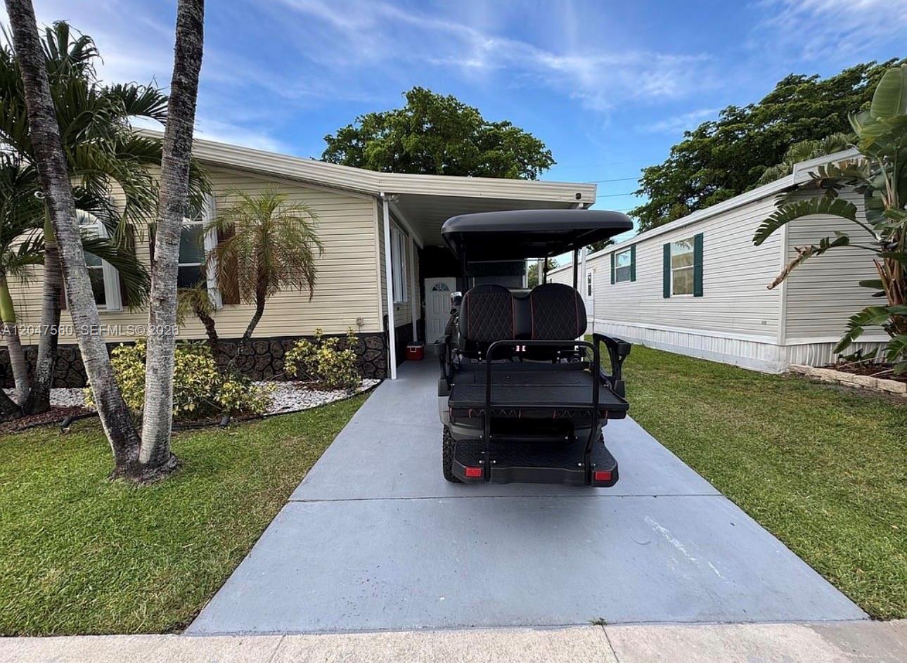 A golf cart is parked on the concrete driveway in front of a mobile home — 1196 SW 112th way, Davie FL 33325, DAVIE, FL