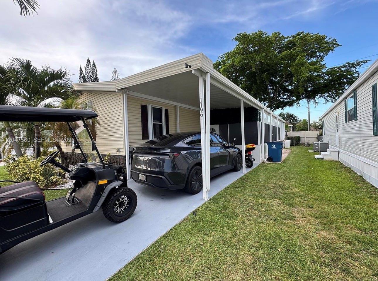 A light-colored mobile home features a carport with a parked car and a golf cart — 1196 SW 112th way, Davie FL 33325, DAVIE, FL