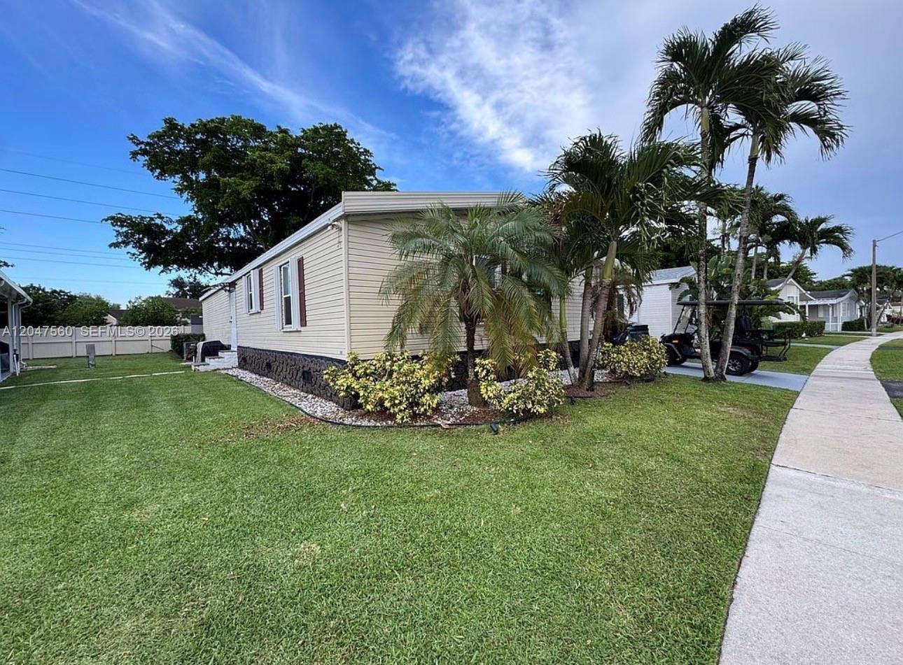A light-colored mobile home sits on a grassy lot with palm trees and a golf cart — 1196 SW 112th way, Davie FL 33325, DAVIE, FL