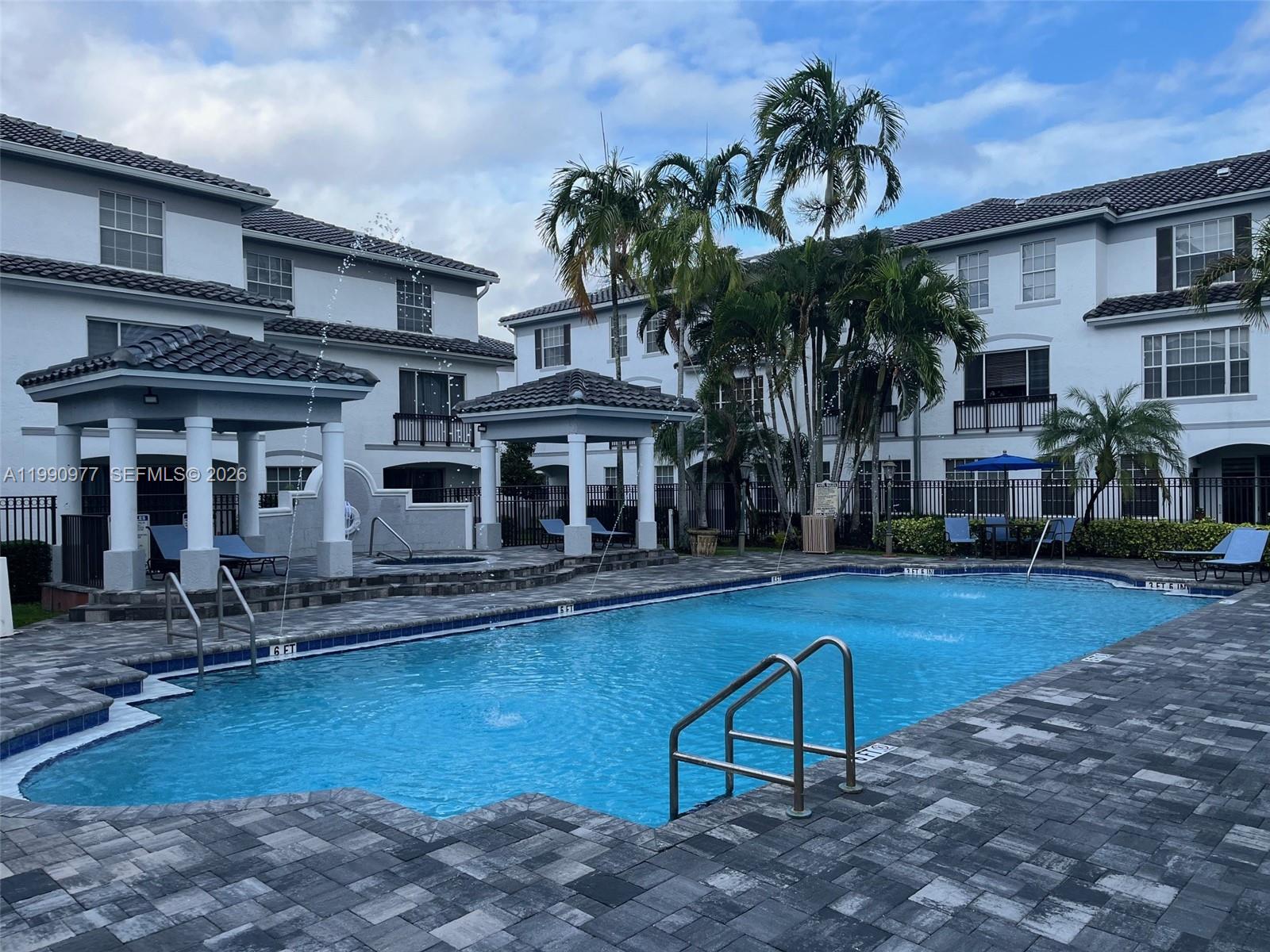 A swimming pool with fountains and two gazebos sits between two multi-story apartment buildings — 781 SW 148th Ave # 1502, Sunrise FL 33325, SUNRISE, FL