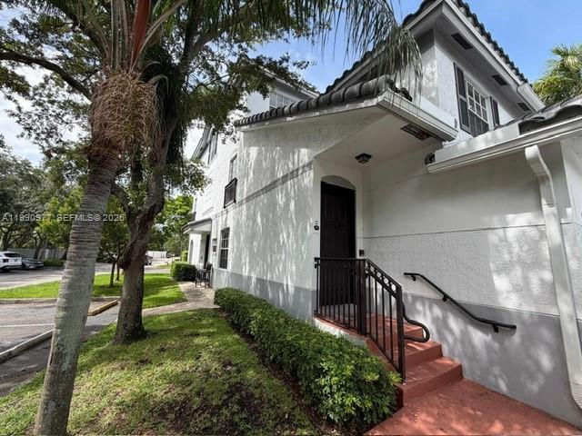 A white two-story building exterior features a dark front door, stairs, and a palm tree — 781 SW 148th Ave # 1502, Sunrise FL 33325, SUNRISE, FL