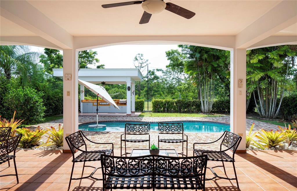A covered patio overlooks a swimming pool and an outdoor kitchen area — 29 HACIENDA CLUB GOLF Y PLAYA, CABO ROJO, PR