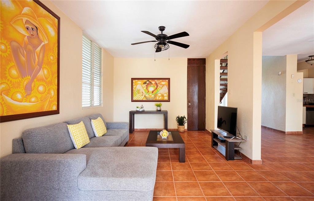 A living room with a gray sectional sofa, tile floors, and a ceiling fan — 29 HACIENDA CLUB GOLF Y PLAYA, CABO ROJO, PR
