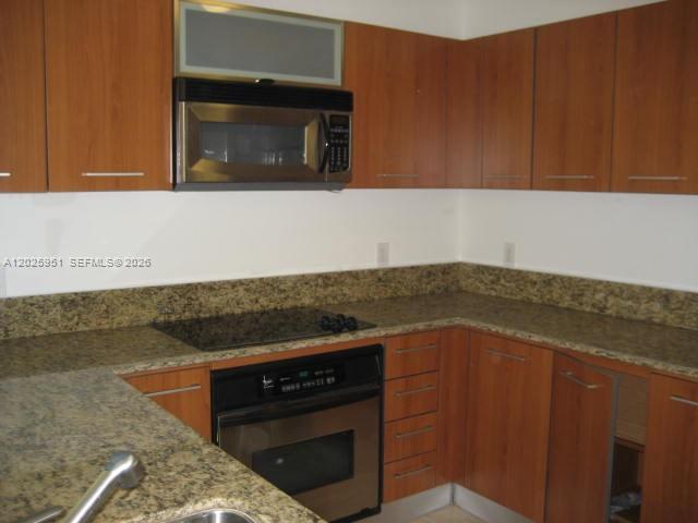 A kitchen features wood cabinets, granite countertops, a built-in microwave, and a stainless steel oven — 9066 SW 73 CT # 1802, Miami FL 33156, MIAMI, FL