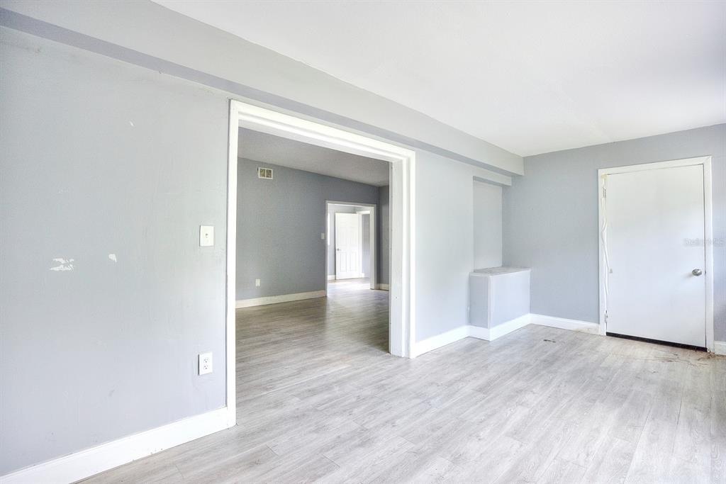 A room with gray walls and light wood-look flooring leads into another connected room — 3009 MARATHON AVENUE, ORLANDO, FL