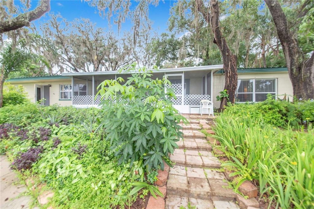 A single-story house with a screened front porch, brick walkway, and lush landscaping — 490 TWIN LAKES BOULEVARD, LAKE ALFRED, FL