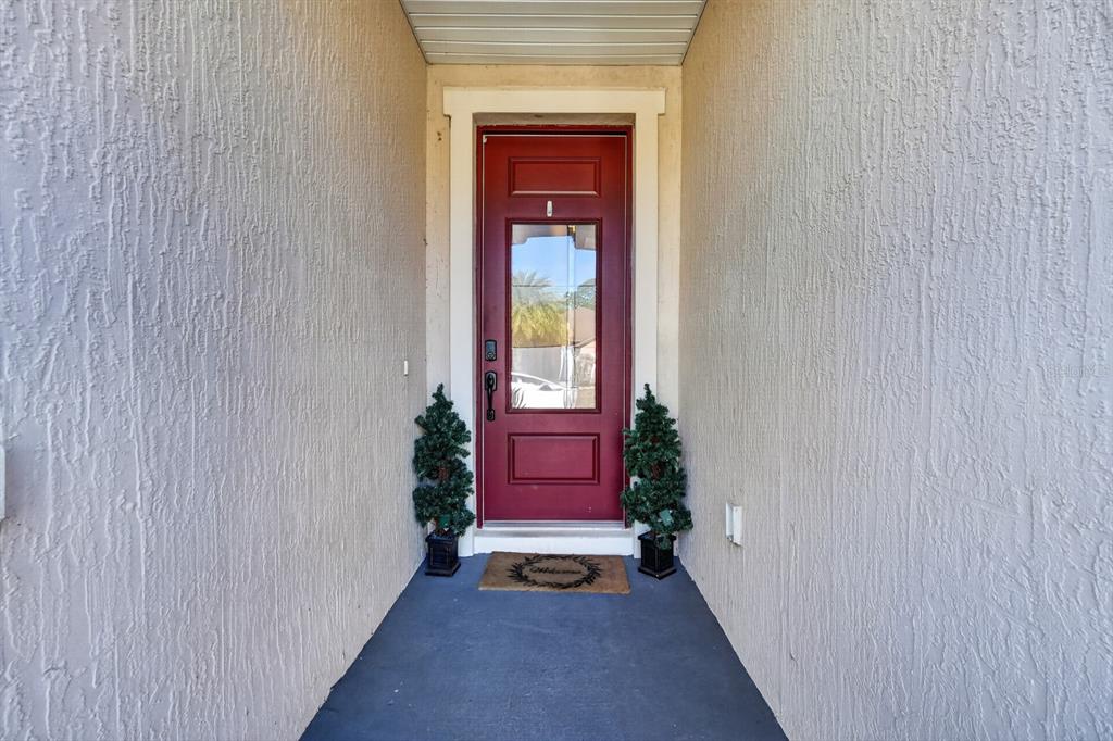 A red front door with a glass panel is flanked by two small potted trees — 344 TUSCANY CHASE DRIVE, DAYTONA BEACH, FL