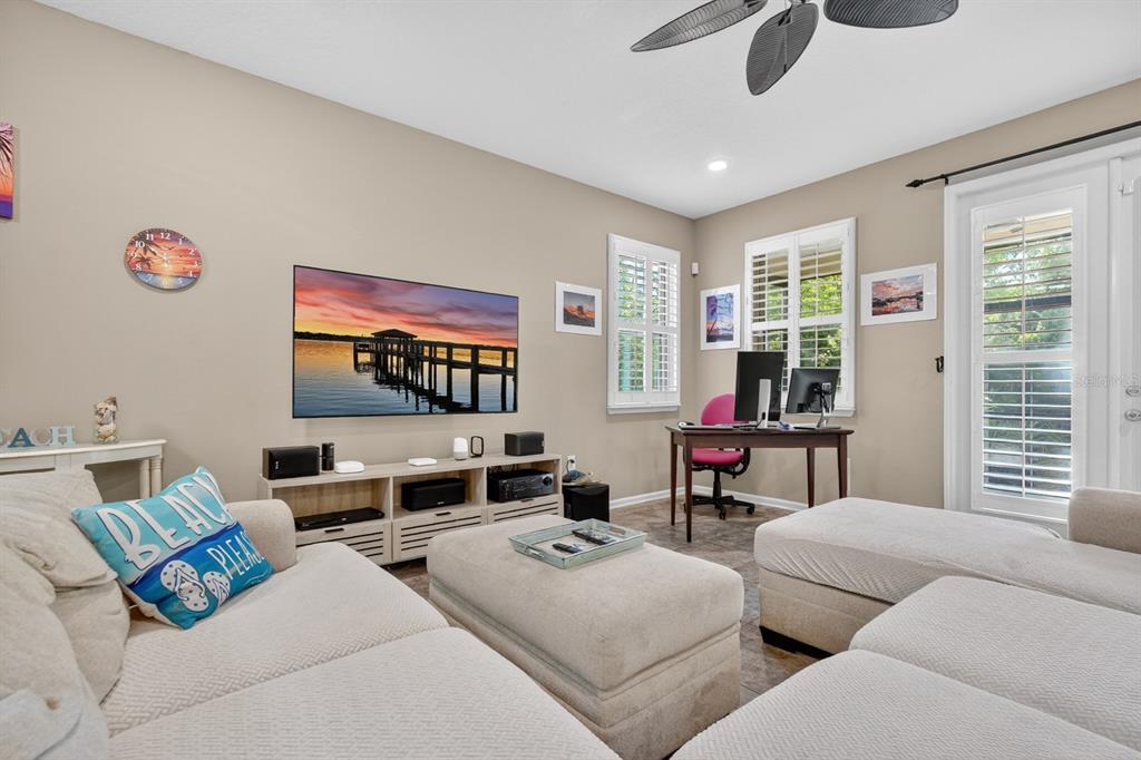 A living room features a large sectional sofa, a television, and a home office area — 344 TUSCANY CHASE DRIVE, DAYTONA BEACH, FL