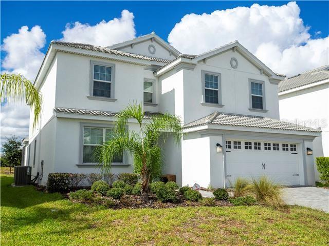 A two-story white stucco house with a two-car garage and a small palm tree — 1568 MAIDSTONE COURT, DAVENPORT, FL