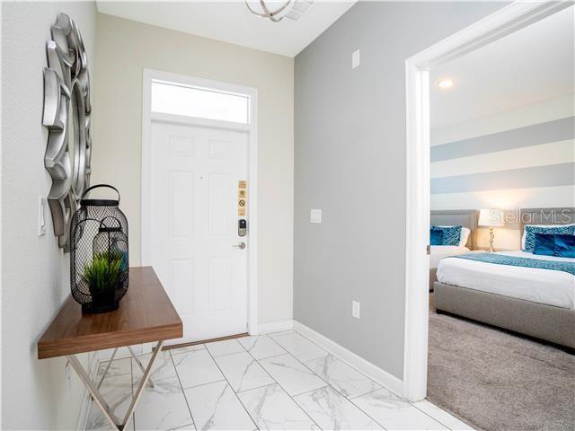 An entryway with a white door, marble-look tile floor, and a view into a bedroom — 1568 MAIDSTONE COURT, DAVENPORT, FL