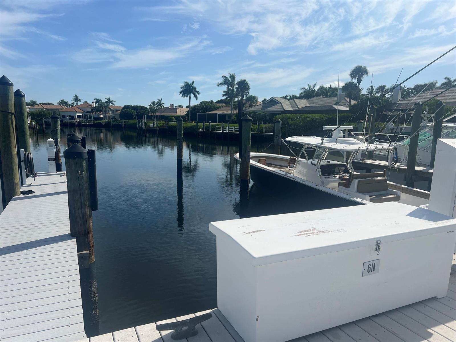 A white boat is docked at a wooden pier in a canal near residential homes — 3232 Casseekey Island Road, Jupiter FL 33477, JUPITER, FL
