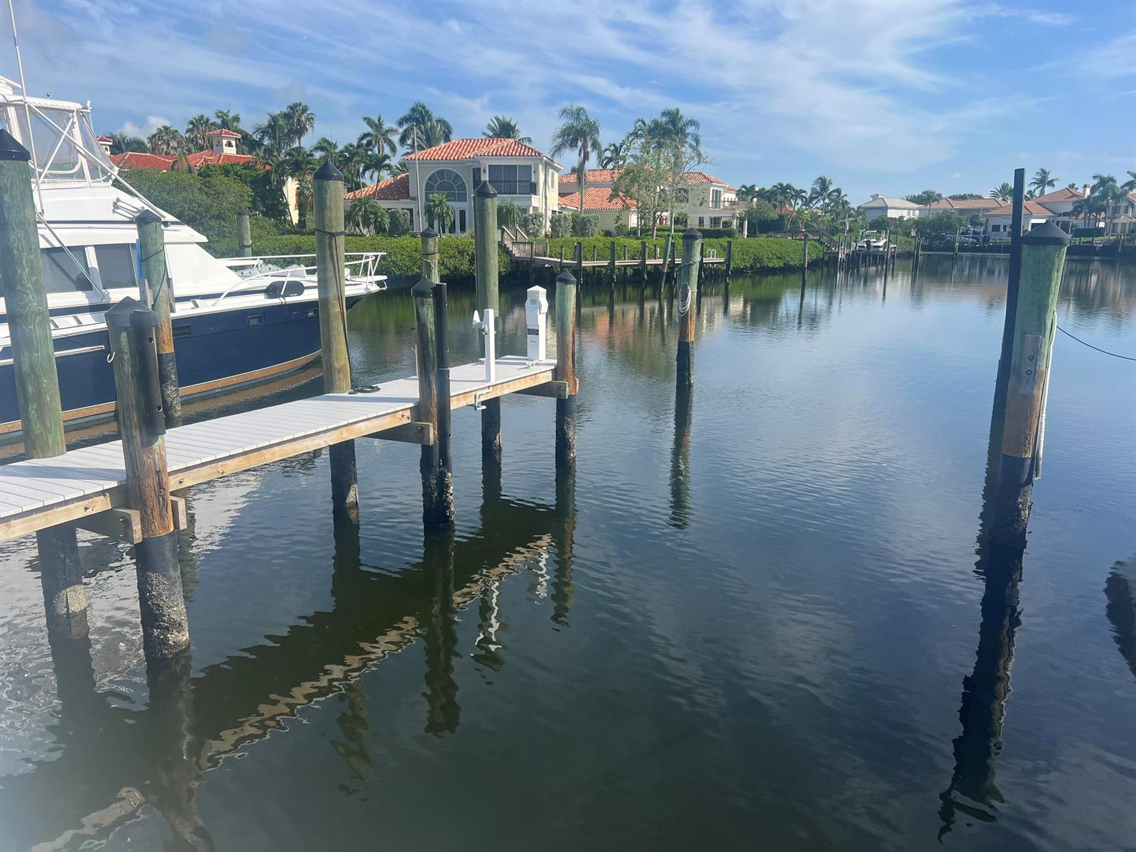 A boat is docked at a wooden pier in a canal lined with residential homes — 3232 Casseekey Island Road, Jupiter FL 33477, JUPITER, FL