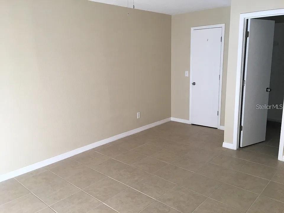 An empty room features beige walls, light-colored tile flooring, and two white interior doors — 330 COLONADE COURT, KISSIMMEE, FL