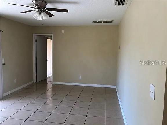 An empty room features beige walls, light-colored floor tiles, and a ceiling fan — 330 COLONADE COURT, KISSIMMEE, FL