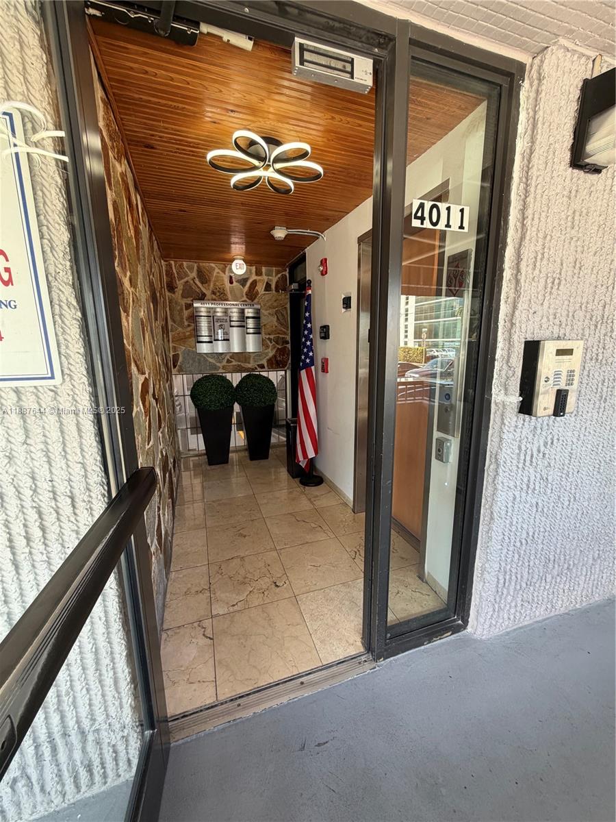 The entrance to a professional building features a glass door, stone wall, and wood ceiling — 4011 W Flagler St # 404, Miami FL 33134, MIAMI, FL