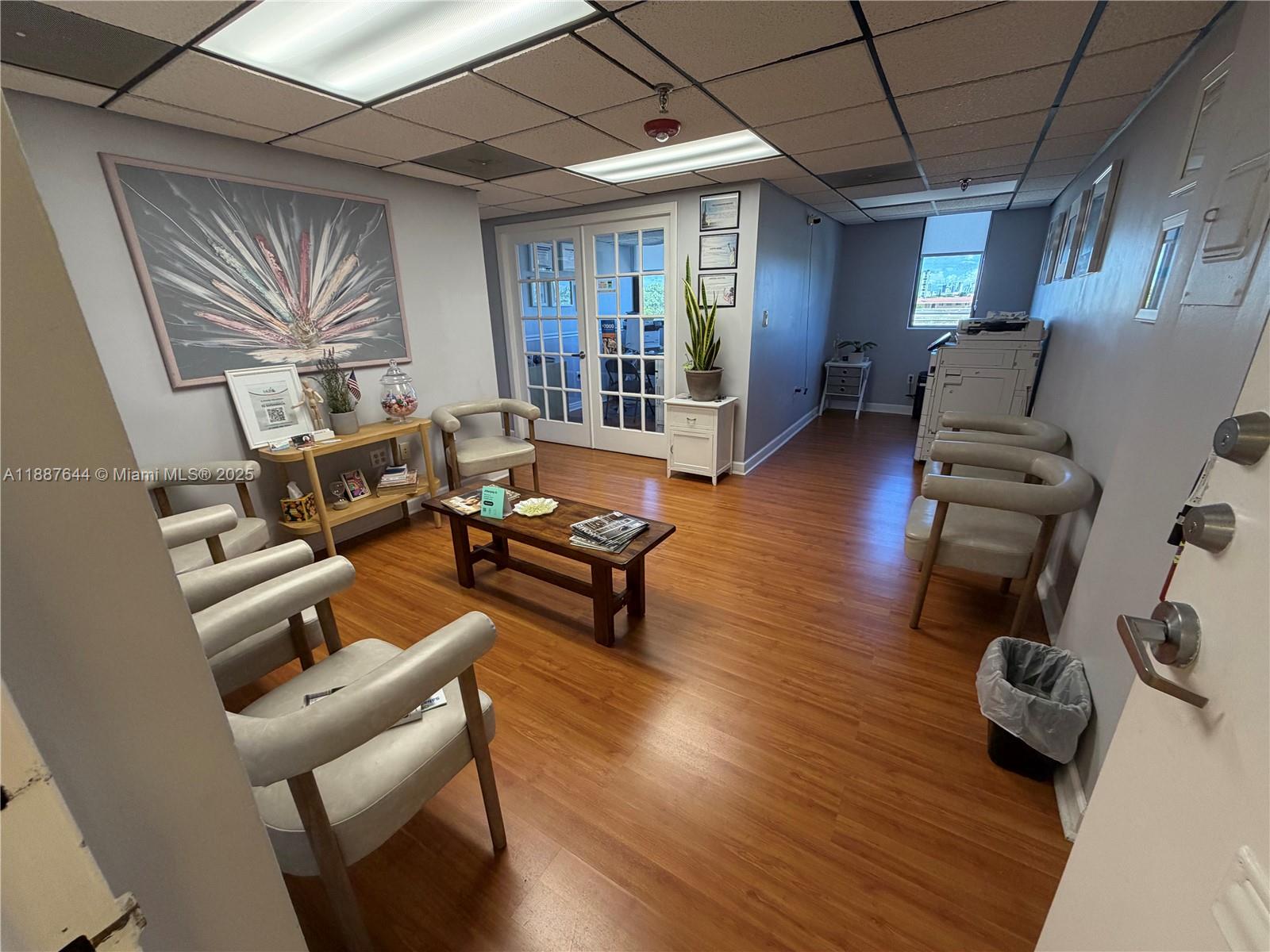 A waiting room features light-colored chairs, a wooden coffee table, and wood-look flooring — 4011 W Flagler St # 404, Miami FL 33134, MIAMI, FL