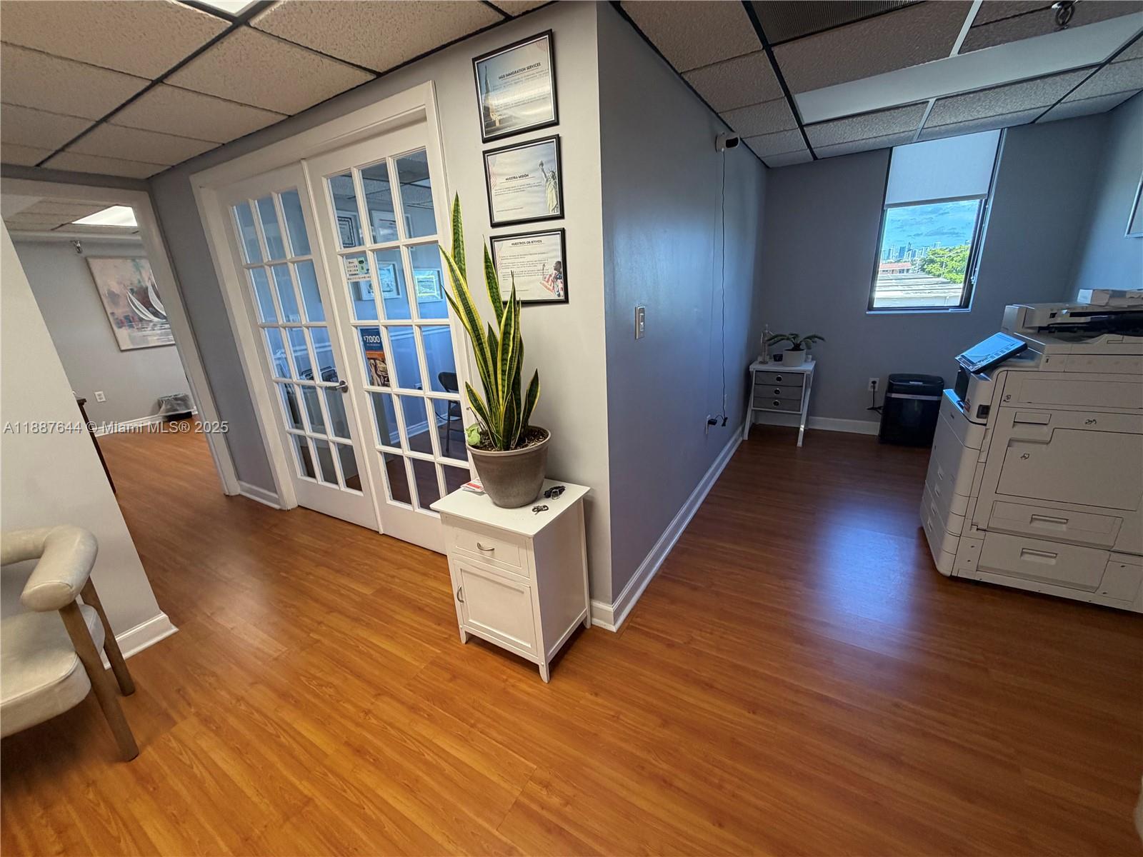 An office space features wood-look flooring, a glass-paneled double door, and a large printer — 4011 W Flagler St # 404, Miami FL 33134, MIAMI, FL