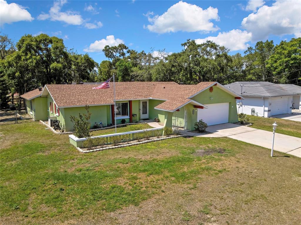 An exterior view of a single-story green house with a brown roof and a garage — 6100 PIEDMONT DRIVE, SPRING HILL, FL