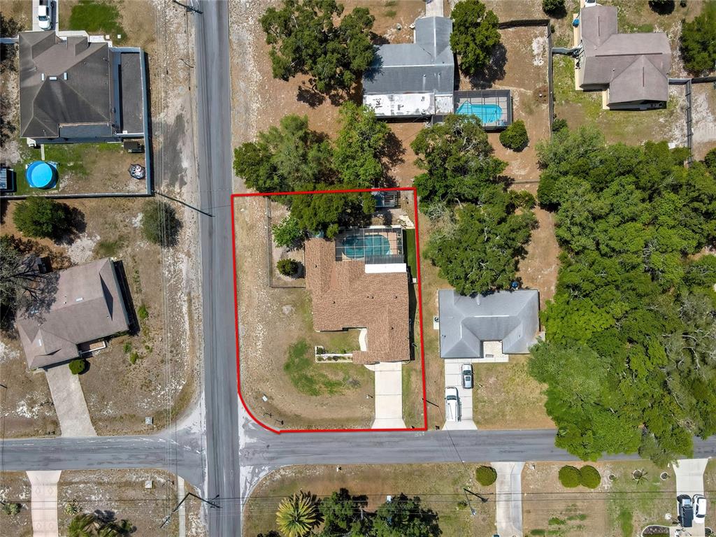 An aerial view shows a single-story house with a pool and a red property boundary — 6100 PIEDMONT DRIVE, SPRING HILL, FL