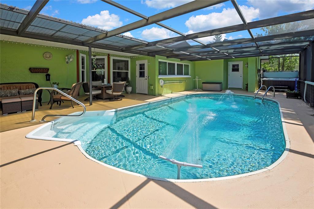 A screened-in patio features a swimming pool with a fountain and a hot tub — 6100 PIEDMONT DRIVE, SPRING HILL, FL