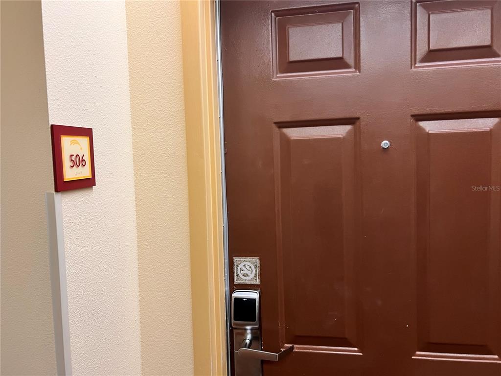 A brown door with a digital lock and a room number sign on the wall — 3000 MAINGATE LANE UNIT 506, KISSIMMEE, FL