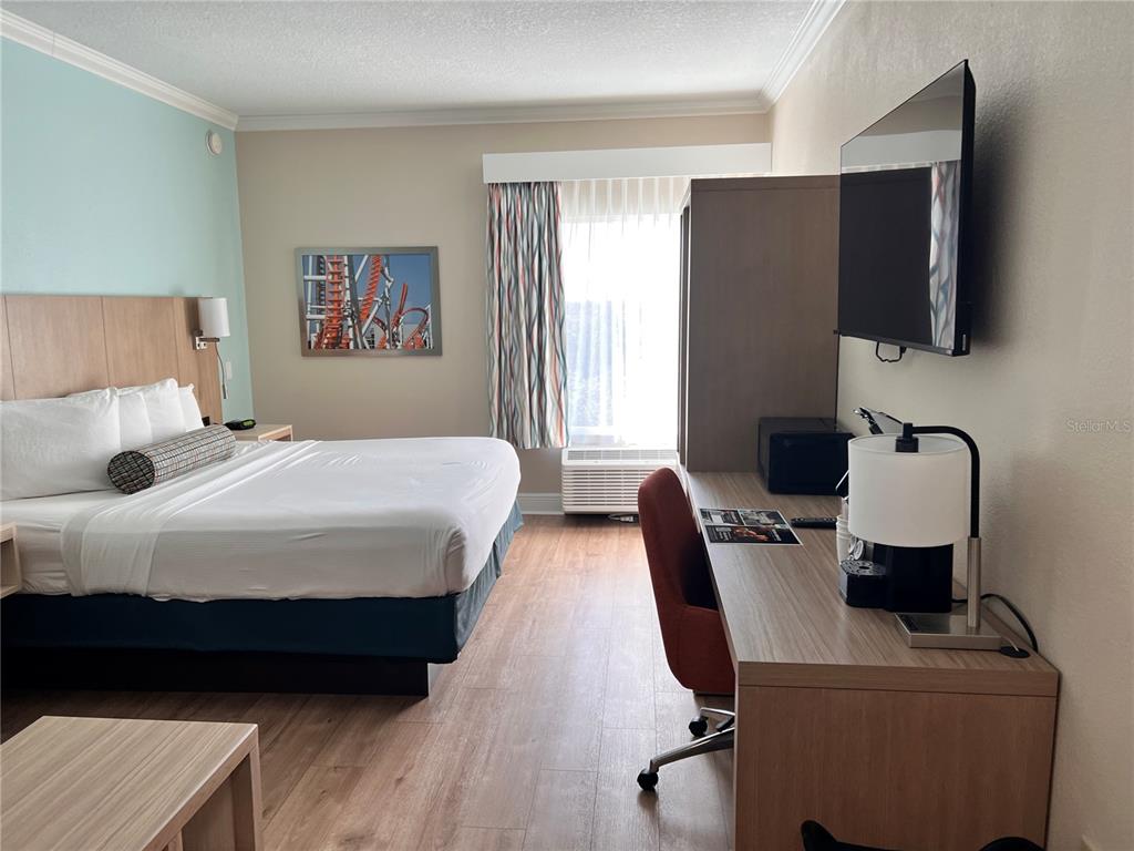 A hotel room features a bed, a desk with a chair, and a wall-mounted television — 3000 MAINGATE LANE UNIT 506, KISSIMMEE, FL