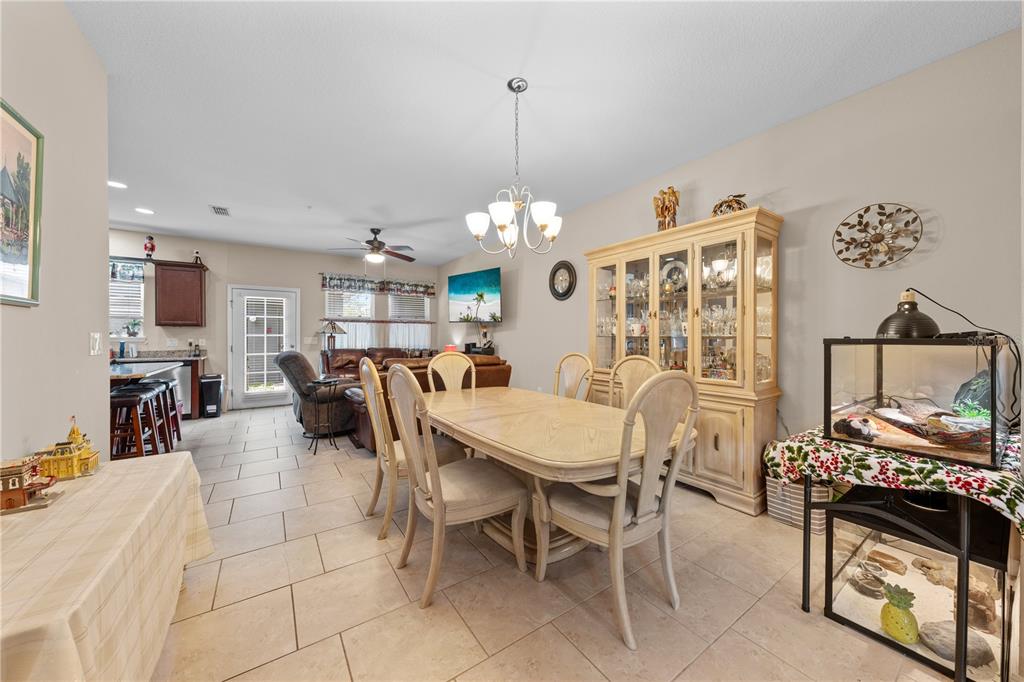 A dining room with a light wood table, hutch, and tile flooring opens to a kitchen — 4811 NATHAN HALE BOULEVARD, ST CLOUD, FL