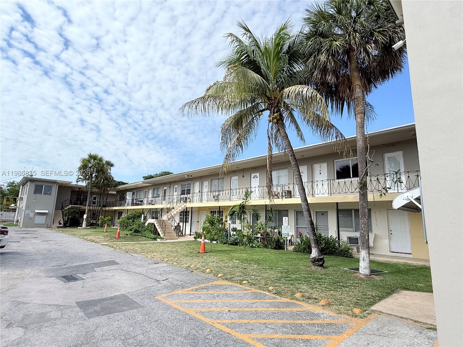A two-story apartment building features exterior walkways, palm trees, and a paved parking lot — 70 NW 77th St # 9, Miami FL 33150, MIAMI, FL