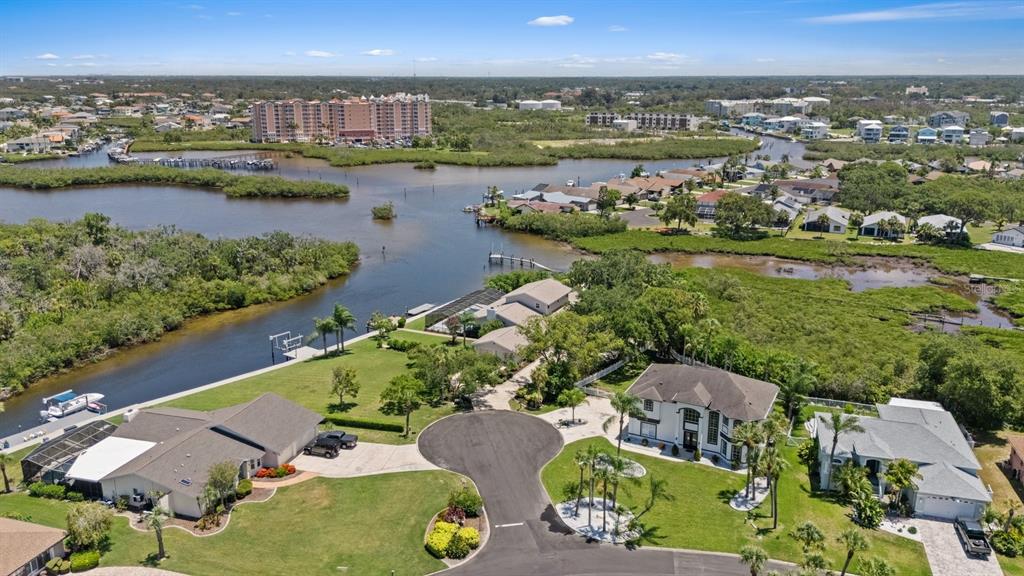 An aerial view shows several waterfront houses with pools and docks along a marshy inlet — 5623 HULL COURT, NEW PORT RICHEY, FL