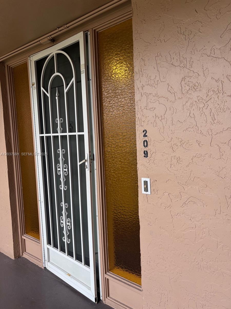 A white metal security door stands next to a wall with the number 209 — SUNRISE, FL