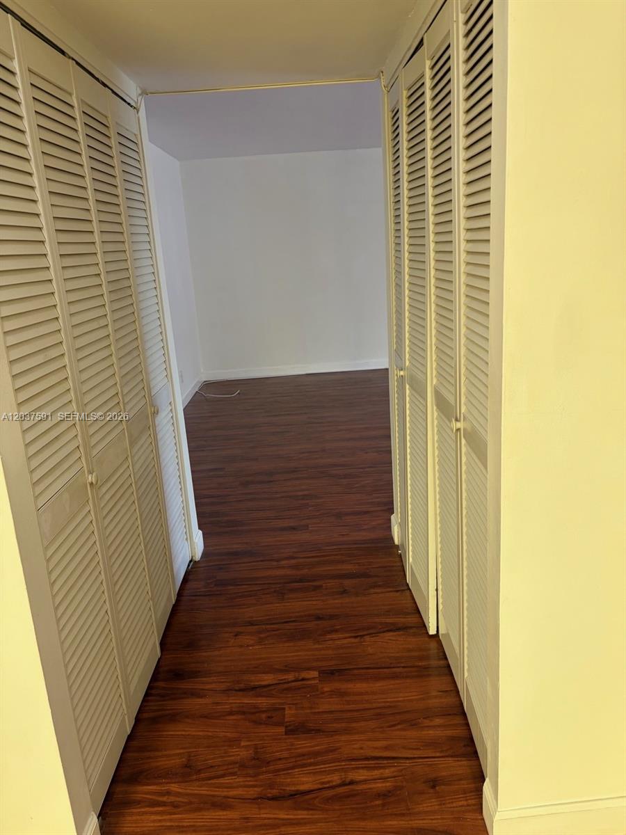 A hallway with louvered closet doors on both sides leads into an empty room — SUNRISE, FL