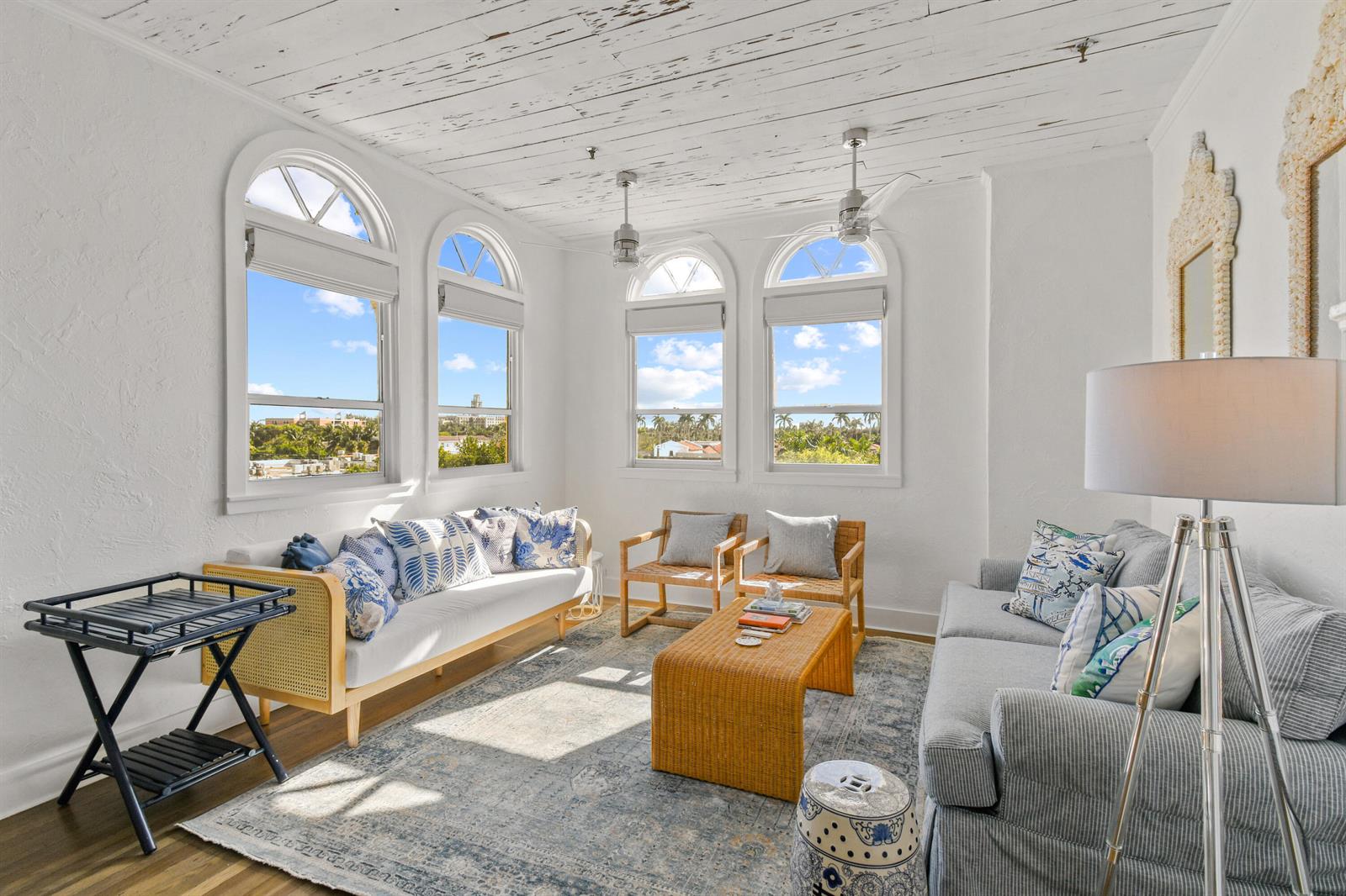 A sunlit living room features white walls, a wood-plank ceiling, arched windows, and coastal-style furniture — 235 Sunrise Avenue, Palm Beach FL 33480, PALM BEACH, FL