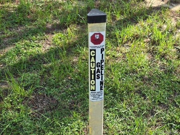 A yellow caution sign for a gas pipeline stands in a grassy field — 2590 N BRENTWOOD CIRCLE, LECANTO, FL