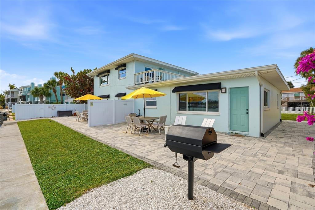 A light blue house features a paved patio, outdoor dining area, and a charcoal grill — 2605 BAY BOULEVARD, INDIAN ROCKS BEACH, FL
