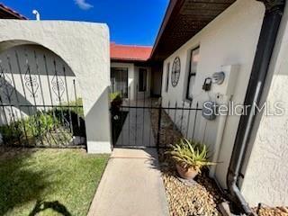A concrete walkway leads through a metal gate toward the entrance of a stucco home — 2725 CLUBHOUSE DRIVE, LAKE WALES, FL