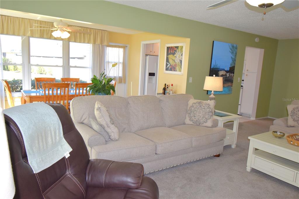 A living room features a beige sofa, a brown recliner, and an adjacent dining area — 121 FERNWOOD CIRCLE UNIT 121, SEMINOLE, FL