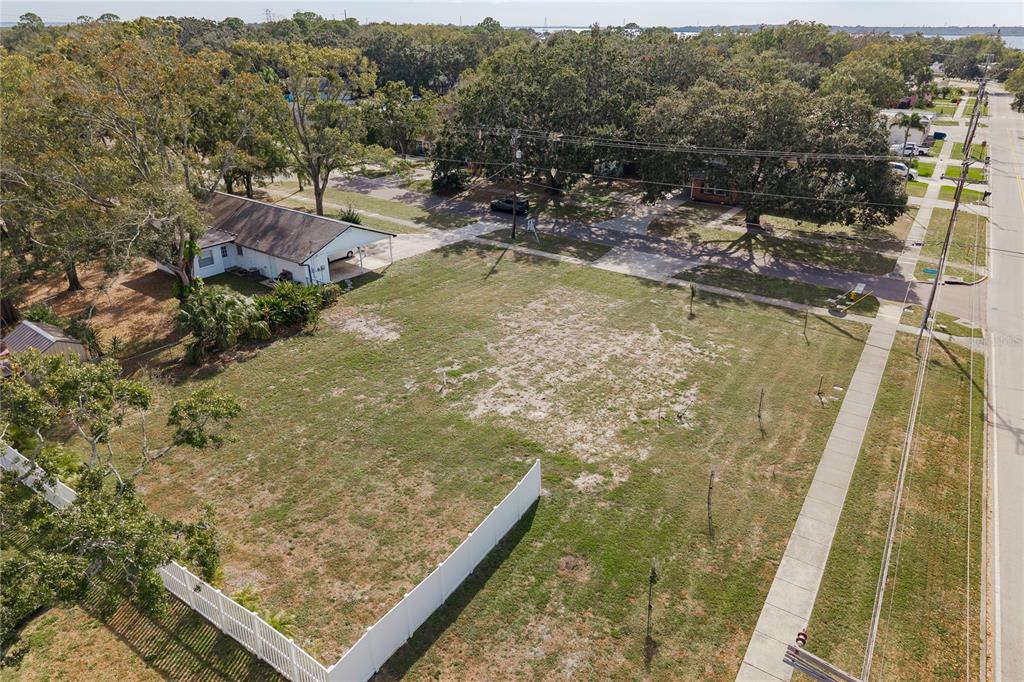 An aerial view shows a large, vacant grassy lot bordered by a sidewalk and trees — 311 WASHINGTON AVENUE, OLDSMAR, FL