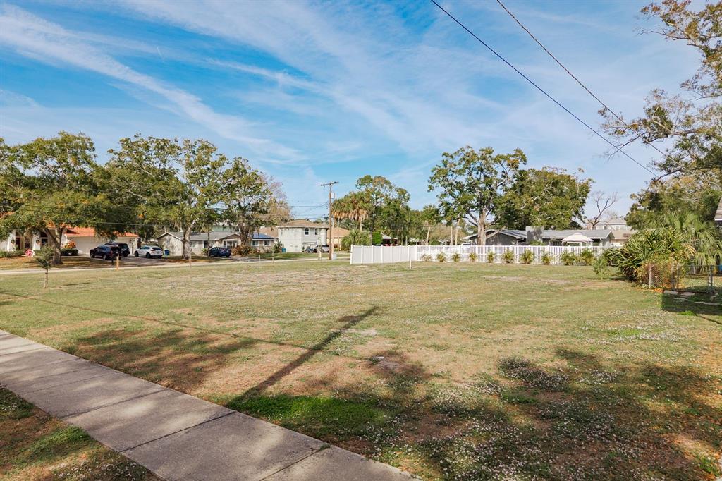 A vacant, grassy residential lot is bordered by a sidewalk and a white fence — 311 WASHINGTON AVENUE, OLDSMAR, FL