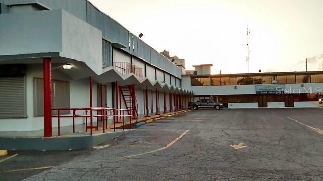 An exterior view of a commercial building with a covered walkway and a parking lot — Ferrocarril St. INT. TORRES ST., PONCE, PR