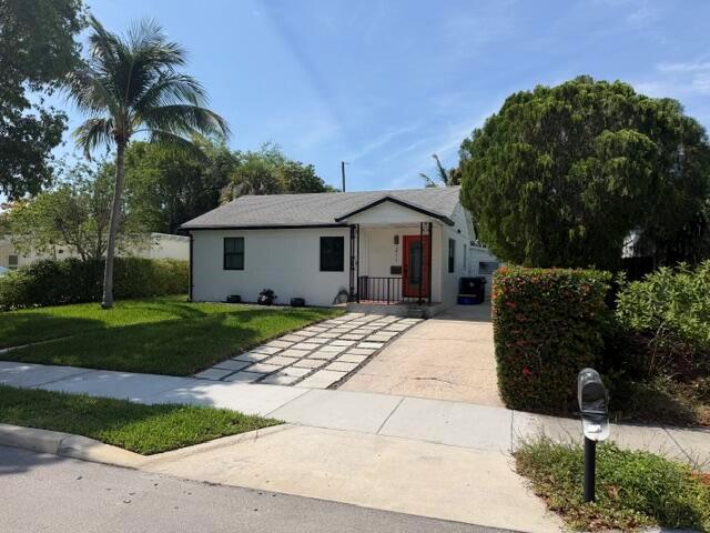 A white single-story house features a red front door, a palm tree, and a driveway — 211 Princeton Drive, FL 33460, FL