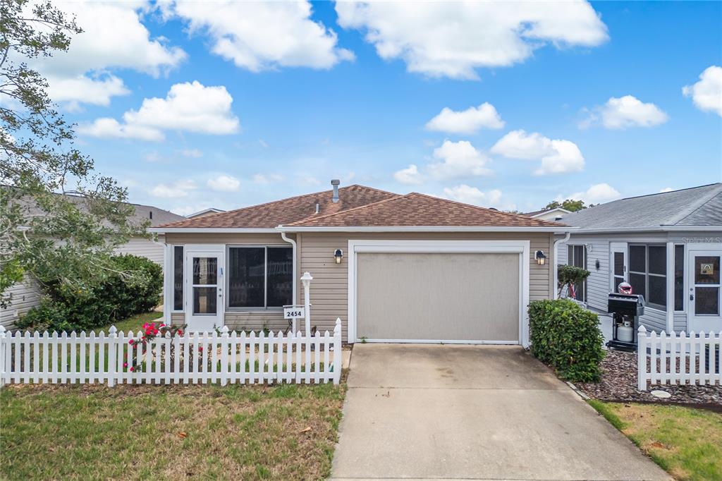 A single-story house with tan siding, a brown roof, and a white picket fence — 2454 SOUTHERN OAK STREET, THE VILLAGES, FL