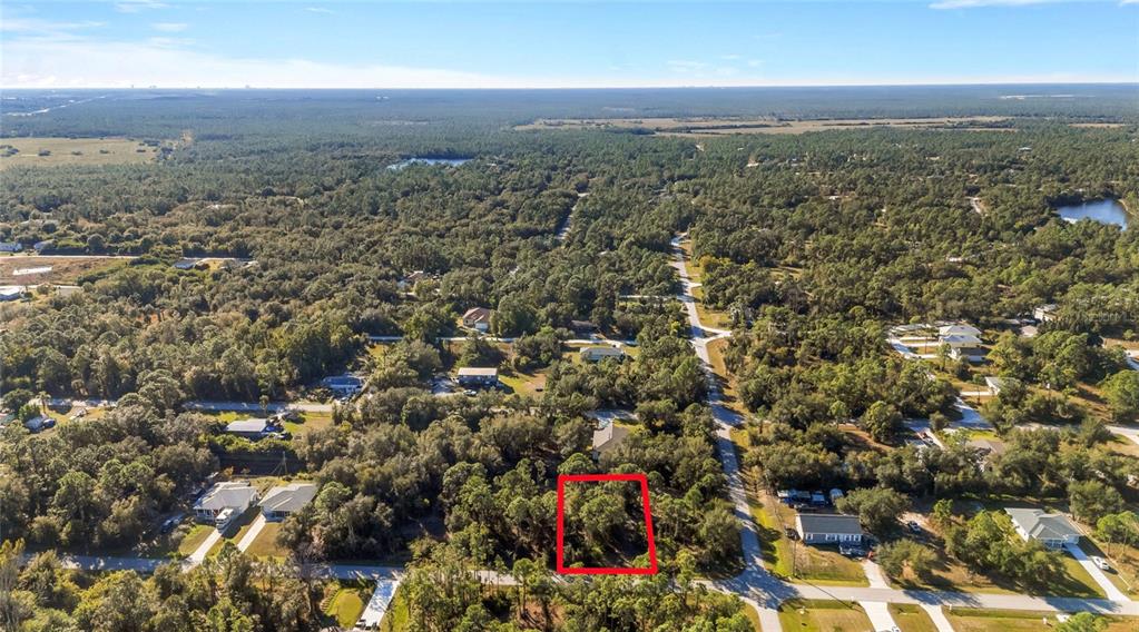 An aerial view shows a rectangular, wooded vacant lot outlined in red within a residential neighborhood — 28149 CHINQUAPIN DRIVE, PUNTA GORDA, FL