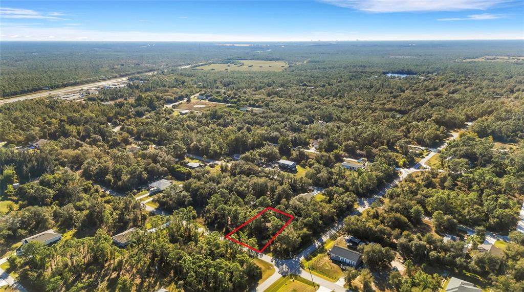 An aerial view shows a rectangular plot of land outlined in red amidst a wooded area — 28149 CHINQUAPIN DRIVE, PUNTA GORDA, FL