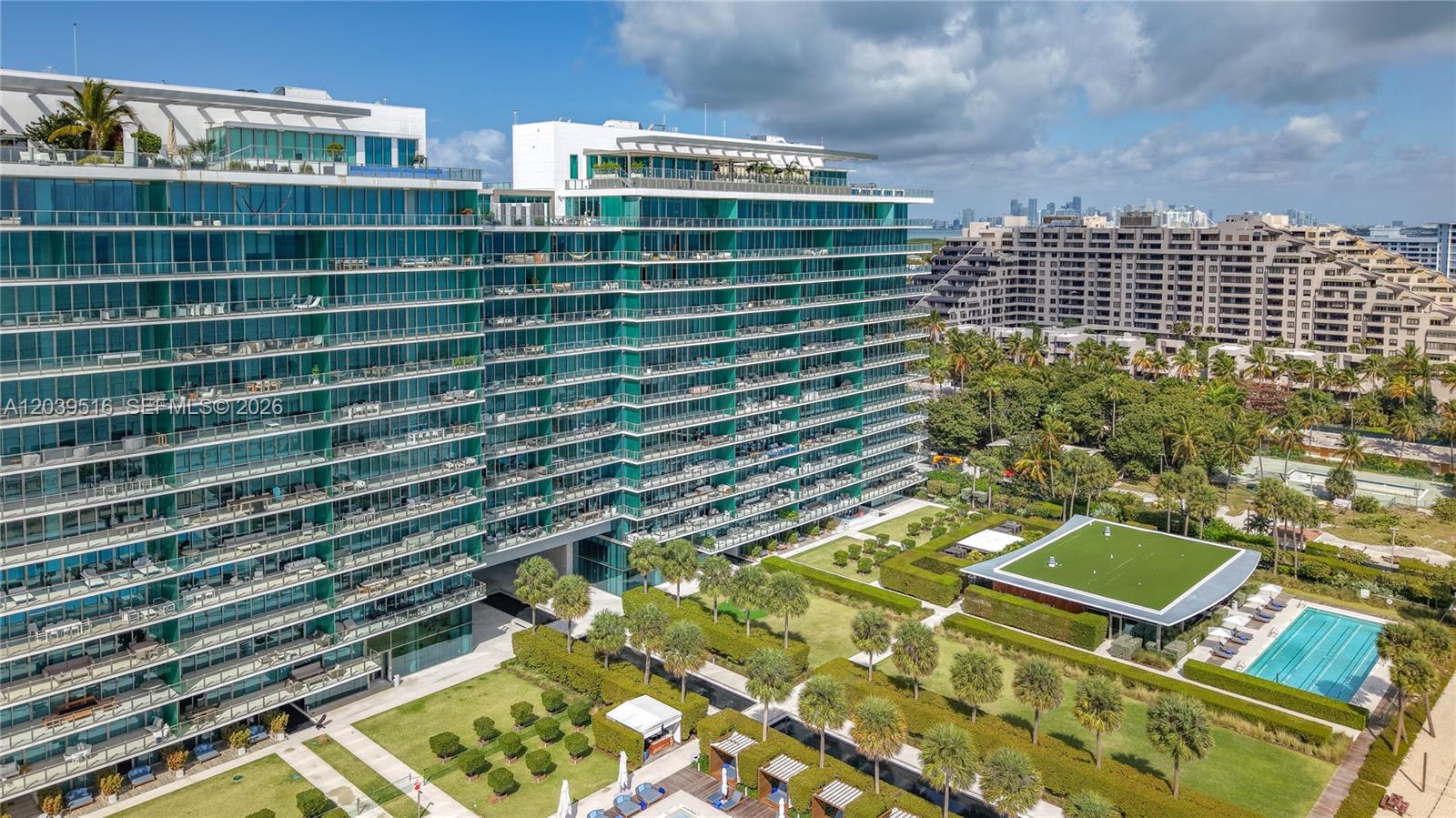 An aerial view shows a modern glass residential building with a pool and landscaped grounds — 350 Ocean Dr # 305N, Key Biscayne FL 33149, KEY BISCAYNE, FL